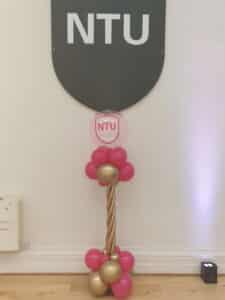 A balloon stand in front of the Nottingham Trent University logo